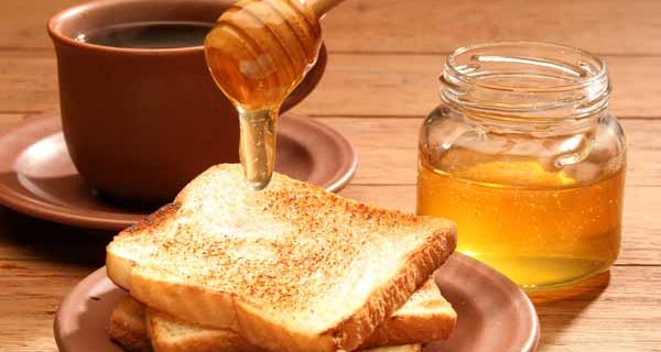 Breakfast scene. Honey pouring over toast bread